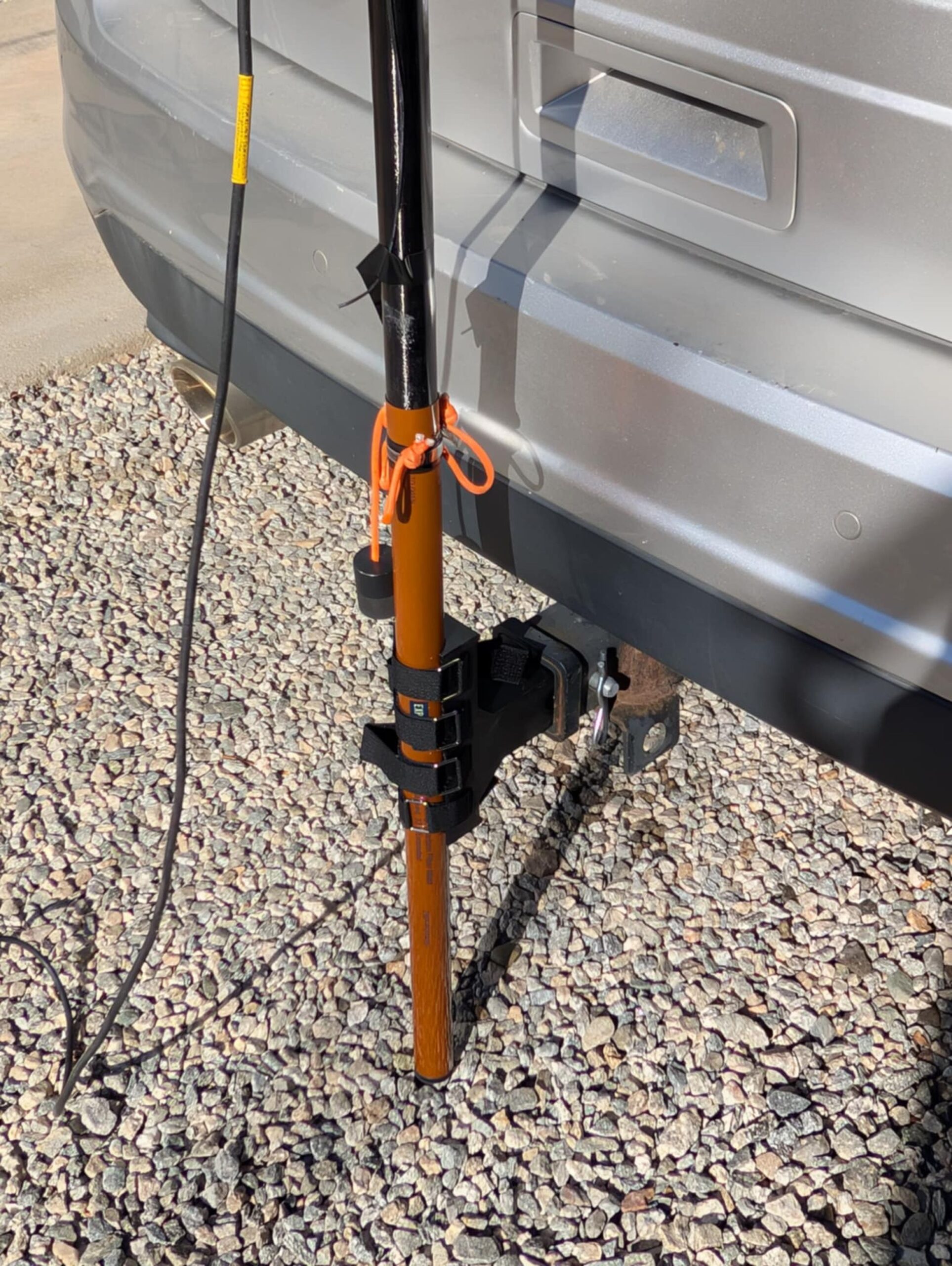 Black hitch mast mount holding an orange mast on an SUV receiver