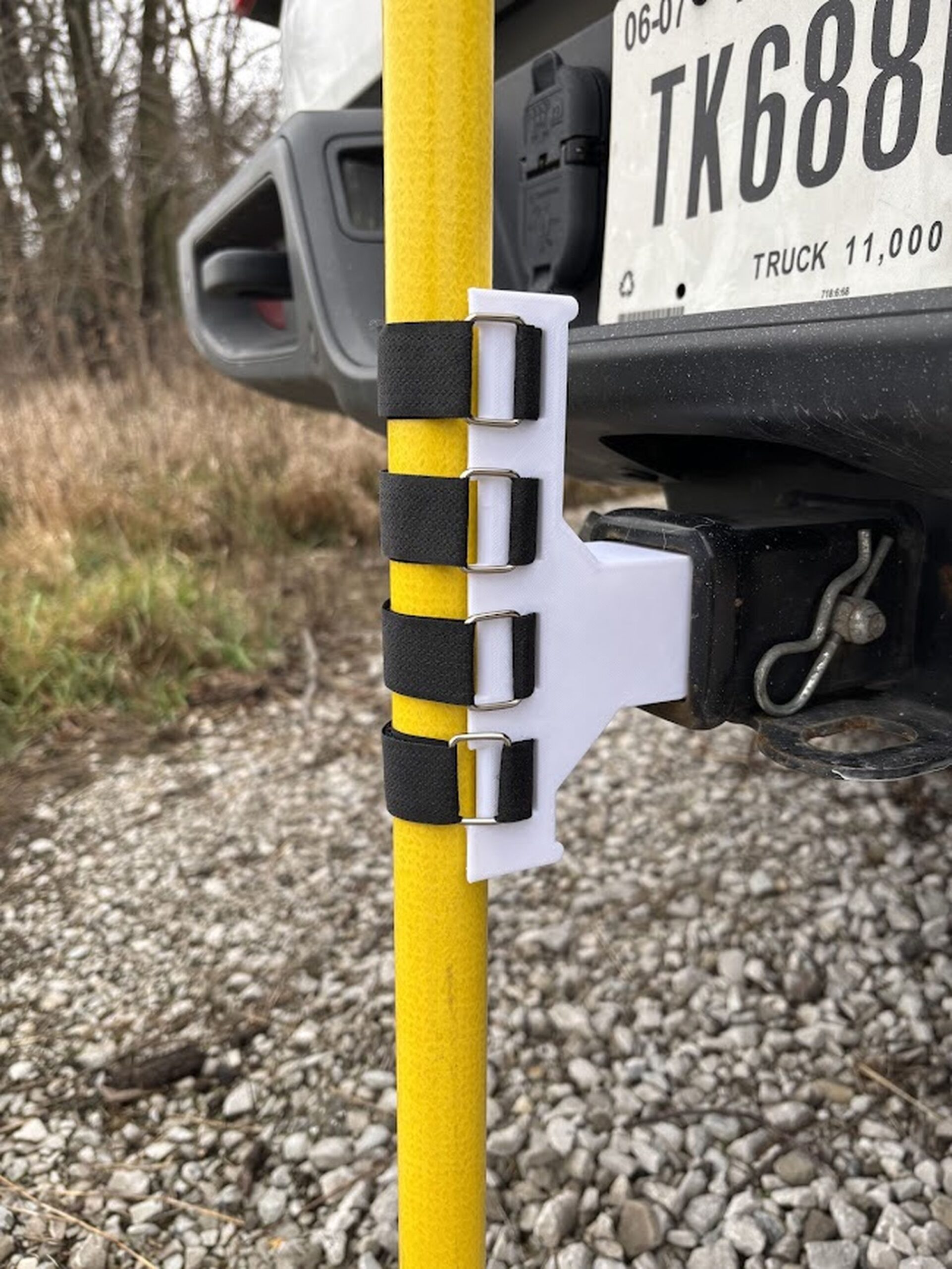 White 3D-printed hitch mast mount holding a yellow fiberglass mast on a truck receiver